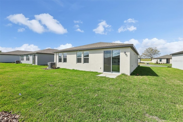 rear view of house with a lawn, central AC, and stucco siding