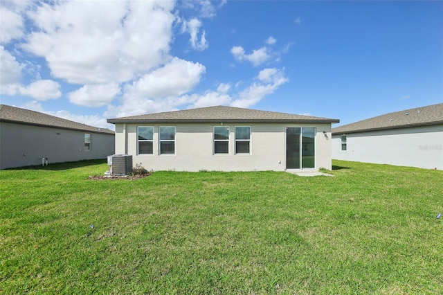 back of property with a yard, central air condition unit, and stucco siding