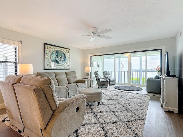 living room with ceiling fan, hardwood / wood-style flooring, and a textured ceiling