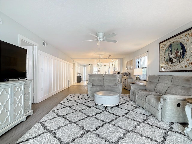 living room featuring ceiling fan with notable chandelier and dark hardwood / wood-style floors