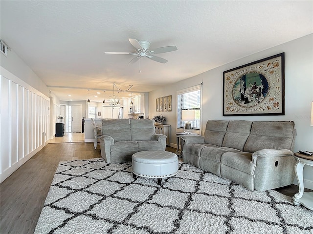 living room featuring ceiling fan with notable chandelier and hardwood / wood-style floors