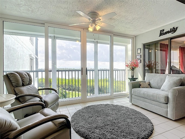 sunroom / solarium with a water view, ceiling fan, and a wealth of natural light