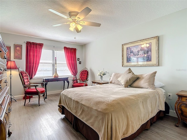 bedroom featuring ceiling fan, hardwood / wood-style flooring, and a textured ceiling