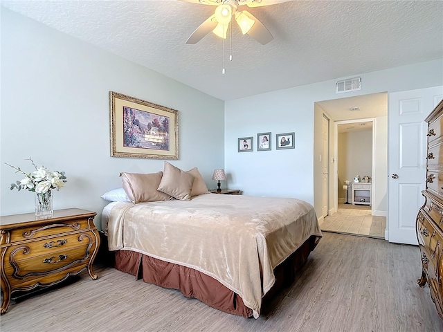 bedroom with light hardwood / wood-style flooring, ceiling fan, and a textured ceiling