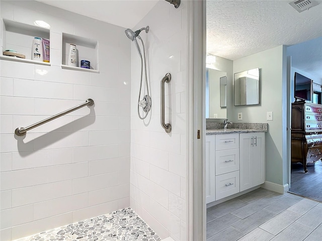 bathroom featuring a tile shower, vanity, a textured ceiling, and hardwood / wood-style floors