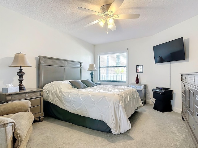 carpeted bedroom with ceiling fan and a textured ceiling