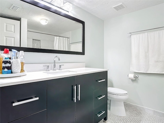 bathroom with a textured ceiling, curtained shower, vanity, and toilet