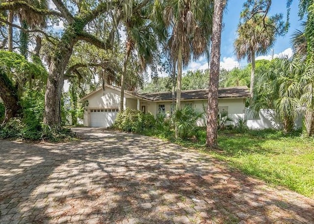 view of front of home with stucco siding, an attached garage, and driveway