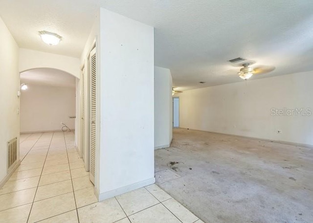 interior space featuring arched walkways, visible vents, a ceiling fan, and light tile patterned floors