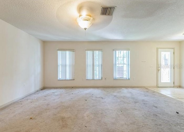 unfurnished room with baseboards, carpet flooring, a textured ceiling, and visible vents