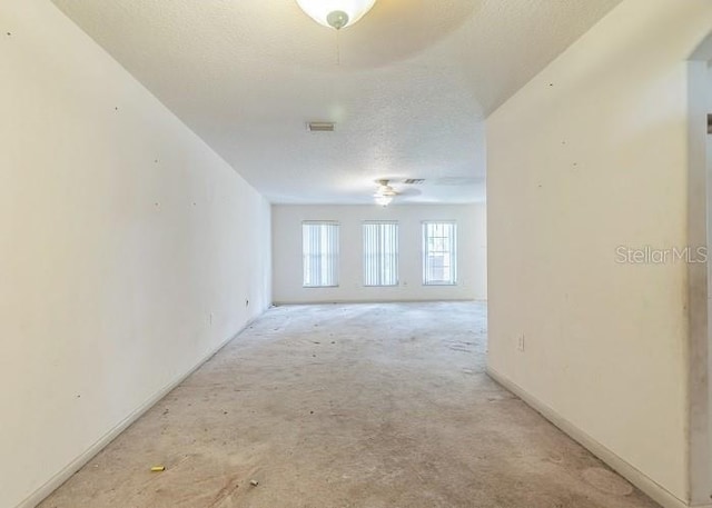 empty room with visible vents, a ceiling fan, baseboards, a textured ceiling, and light colored carpet
