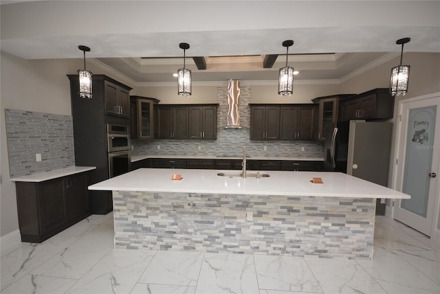 kitchen with a center island with sink, decorative light fixtures, sink, and wall chimney range hood