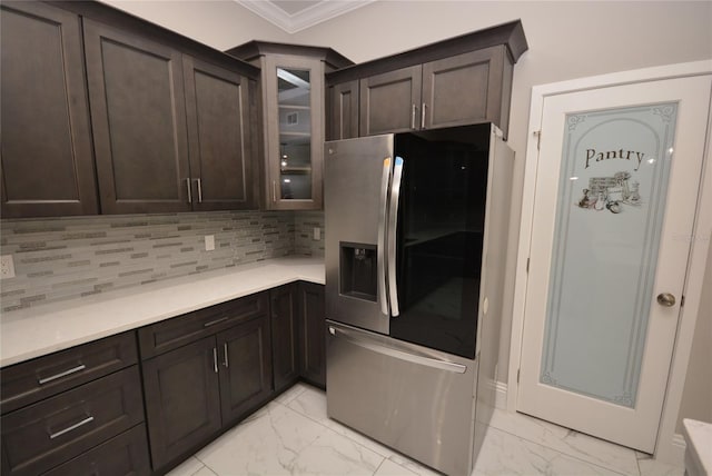 kitchen featuring ornamental molding, backsplash, stainless steel fridge, and dark brown cabinets