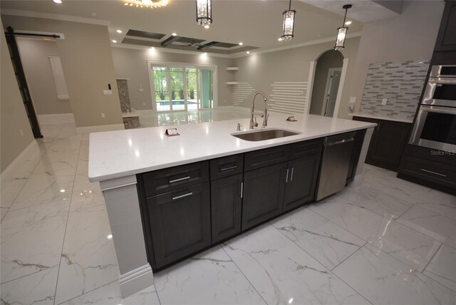 kitchen with an island with sink, sink, ornamental molding, hanging light fixtures, and appliances with stainless steel finishes