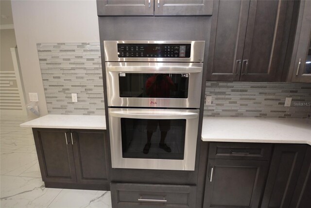 kitchen featuring dark brown cabinets, stainless steel double oven, and tasteful backsplash