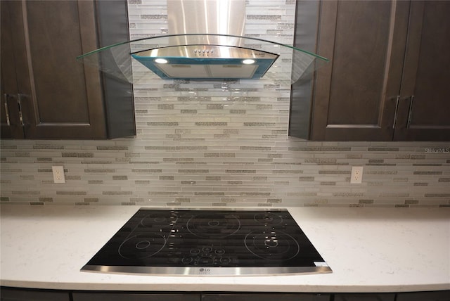 kitchen with dark brown cabinets, island exhaust hood, black cooktop, and tasteful backsplash