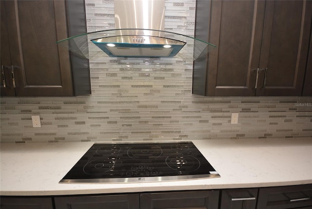 kitchen with island range hood, black cooktop, dark brown cabinetry, and decorative backsplash