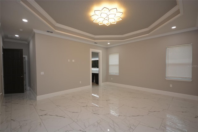 empty room with ornamental molding and a tray ceiling