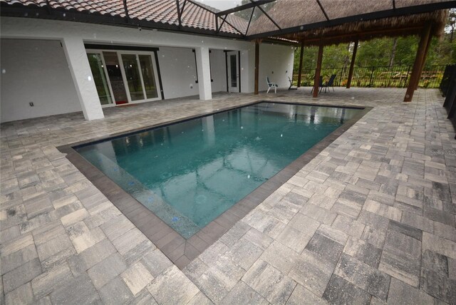 view of pool featuring glass enclosure and a patio