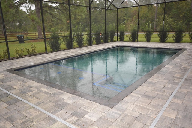 view of swimming pool featuring glass enclosure and a patio area