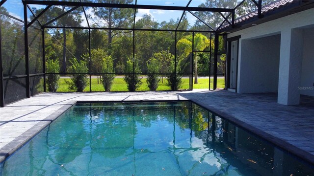 view of pool featuring glass enclosure and a patio area