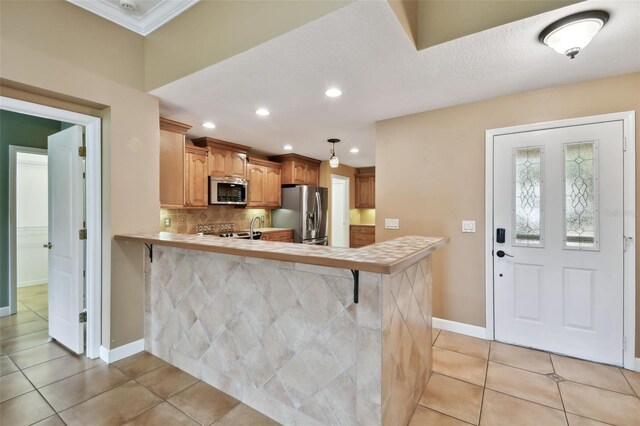 kitchen featuring light tile patterned floors, kitchen peninsula, decorative light fixtures, appliances with stainless steel finishes, and a breakfast bar area