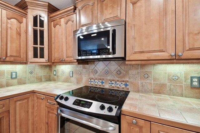 kitchen featuring tile counters, stainless steel appliances, and backsplash