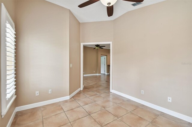 empty room with lofted ceiling, ceiling fan, and light tile patterned floors