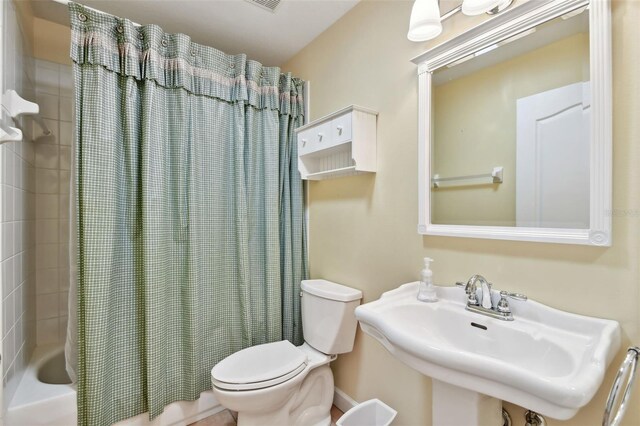 full bathroom with shower / tub combo with curtain, sink, and toilet