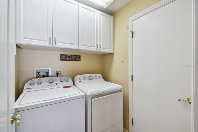 laundry room with washing machine and dryer and cabinets