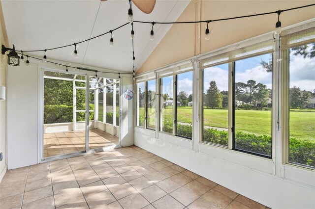 unfurnished sunroom featuring ceiling fan, a wealth of natural light, and vaulted ceiling