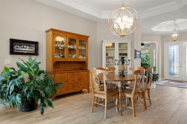 dining space with light hardwood / wood-style flooring, a raised ceiling, ceiling fan with notable chandelier, and crown molding