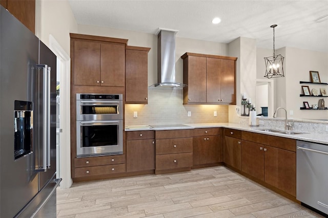 kitchen with light wood-type flooring, a chandelier, sink, wall chimney range hood, and stainless steel appliances