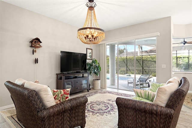 living room with light wood-type flooring and ceiling fan with notable chandelier