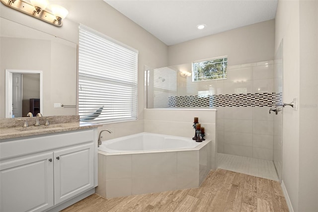 bathroom featuring wood-type flooring, plenty of natural light, vanity, and separate shower and tub