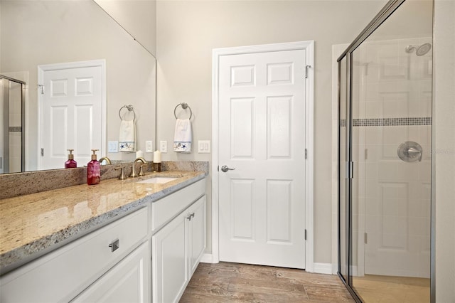 bathroom with wood-type flooring, walk in shower, and vanity