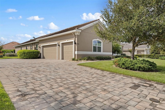 ranch-style house featuring a garage and a front lawn