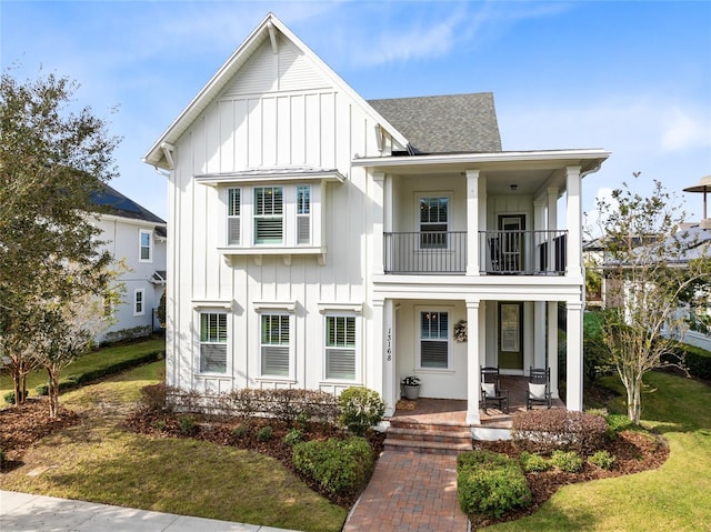 modern inspired farmhouse featuring a front yard, a porch, and a balcony