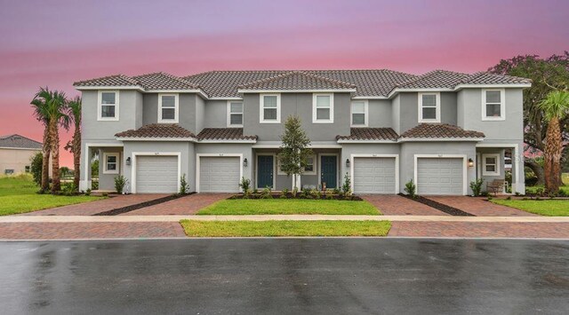 195 River Front Way, Edgewater, FL 32141 - townhome / multi-family property with driveway, a garage, a tiled roof, and stucco siding