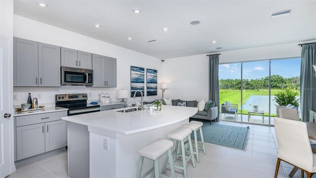 195 River Front Way, Edgewater, FL 32141 - kitchen with stainless steel appliances, gray cabinets, light tile patterned floors, an island with sink, and light countertops