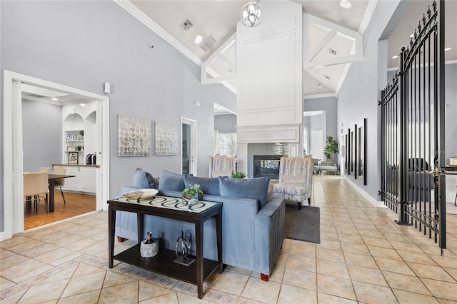 living room with light tile patterned flooring, ornamental molding, high vaulted ceiling, and a large fireplace