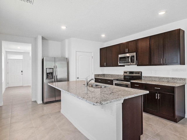 kitchen featuring dark brown cabinetry, sink, a textured ceiling, a kitchen island with sink, and stainless steel appliances