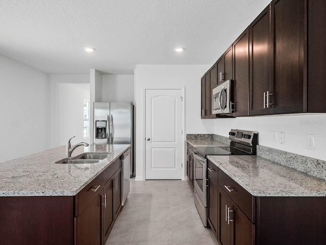 kitchen with dark brown cabinetry, sink, a textured ceiling, a center island with sink, and stainless steel appliances