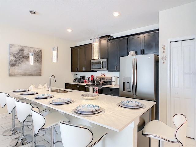 kitchen with an island with sink, stainless steel appliances, decorative light fixtures, and sink