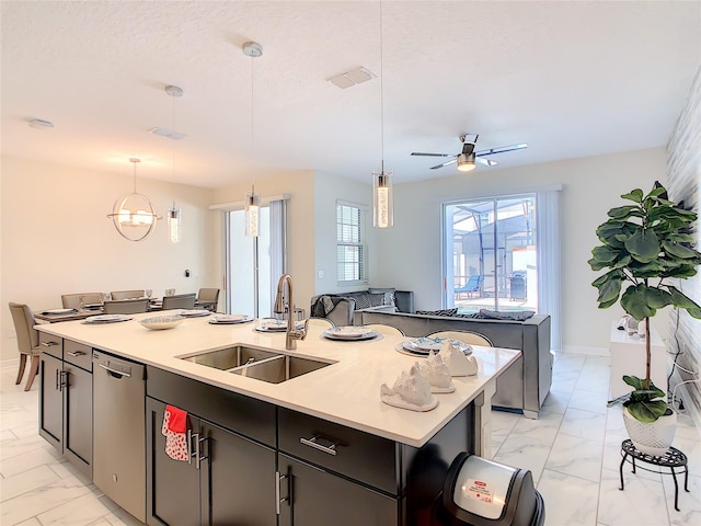 kitchen featuring ceiling fan with notable chandelier, decorative light fixtures, a kitchen island with sink, and sink