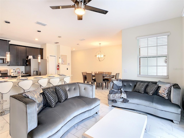 living room featuring ceiling fan with notable chandelier and sink