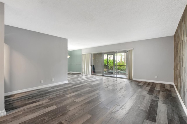 unfurnished room featuring a textured ceiling, wooden walls, and dark hardwood / wood-style floors