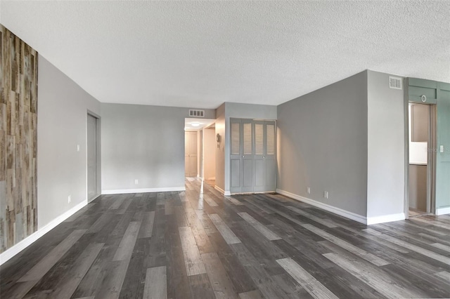 spare room featuring a textured ceiling and dark hardwood / wood-style flooring