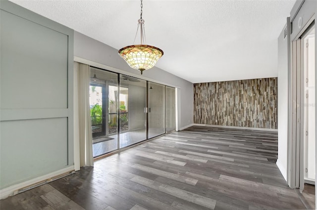 interior space with a textured ceiling, wood walls, and dark hardwood / wood-style flooring