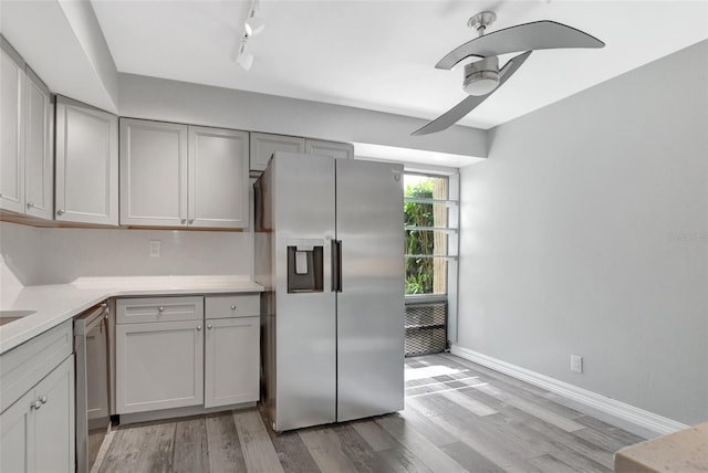 kitchen with rail lighting, gray cabinets, stainless steel appliances, ceiling fan, and light hardwood / wood-style flooring